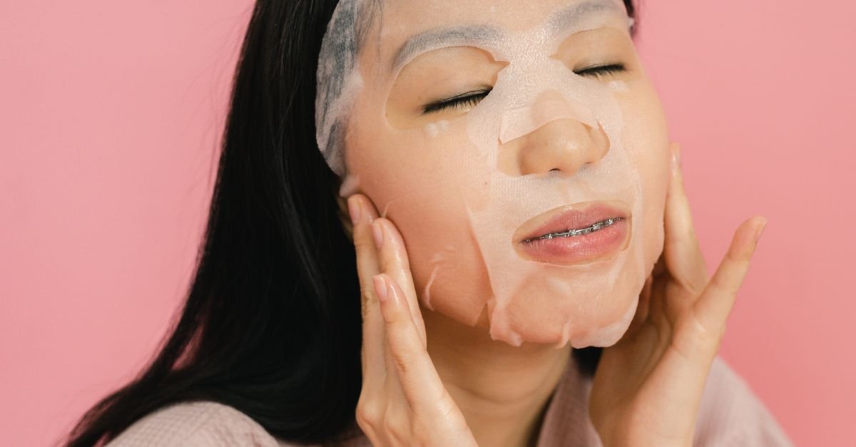 Woman applying a Korean hydrating facial sheet mask at home