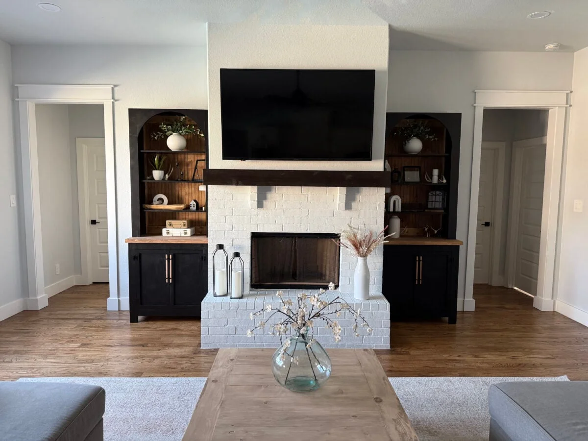 Two black arched bookcases flanking a fireplace, finished and styled
