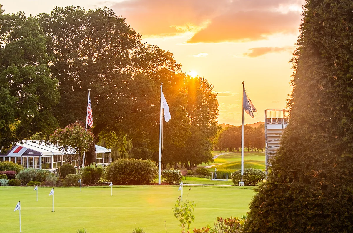 Golf course green and clubhouse glowing at golden hour sunset