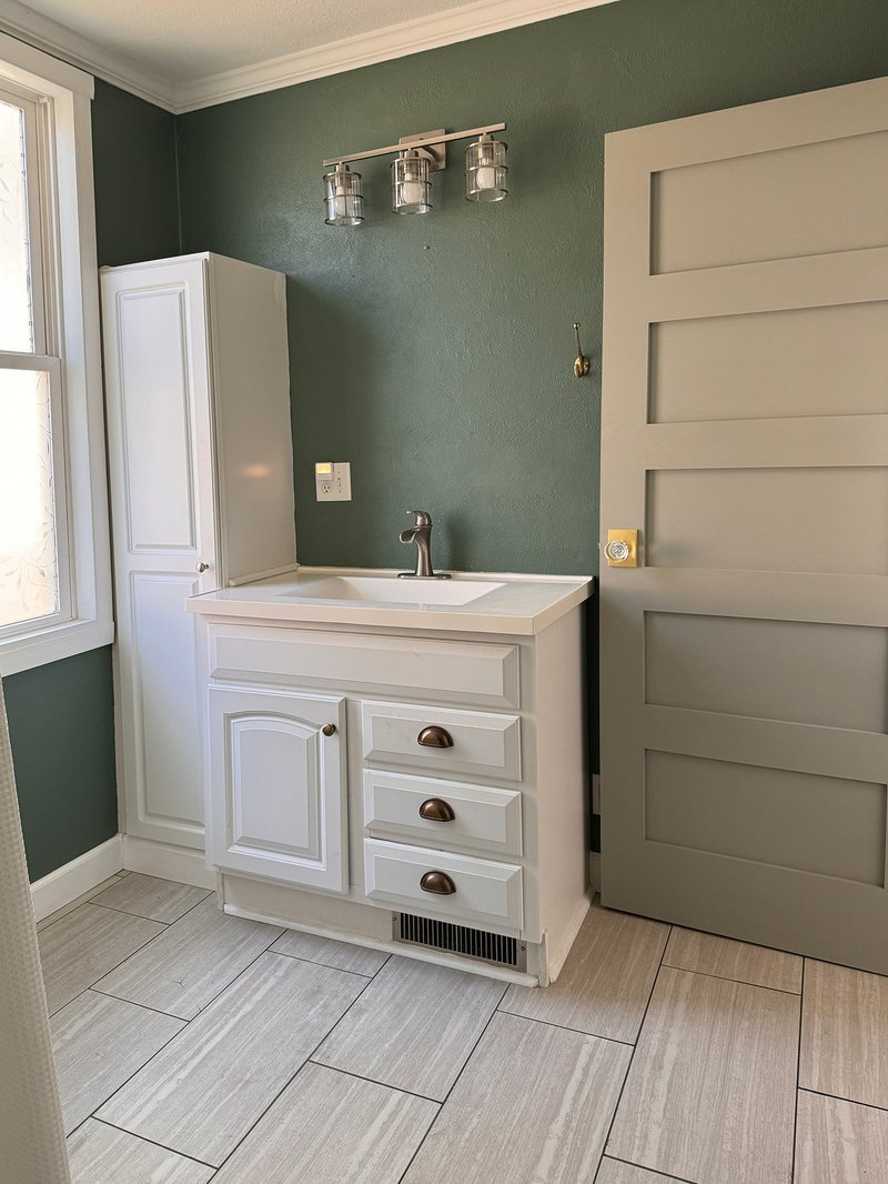 Light wood vanity with brass fixtures in a warm small bathroom