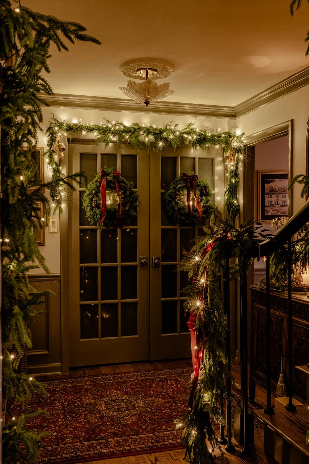 Cozy foyer with greenery and warm holiday lighting at night