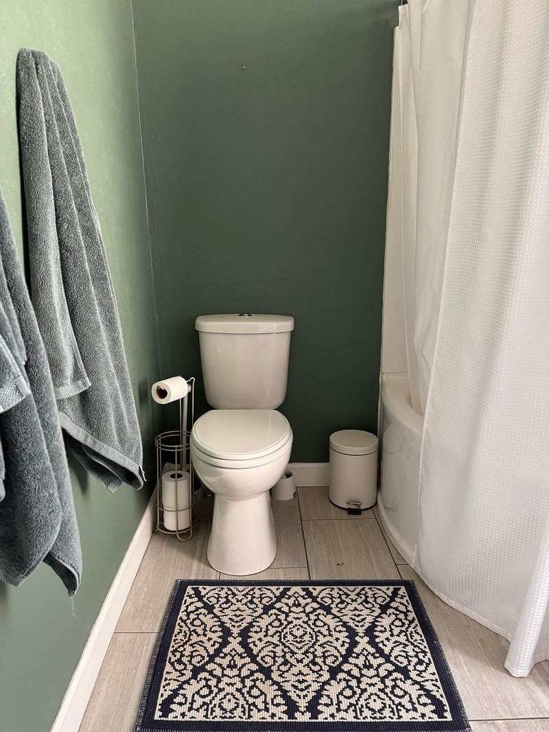 Small bathroom corner with sage green walls and white vanity