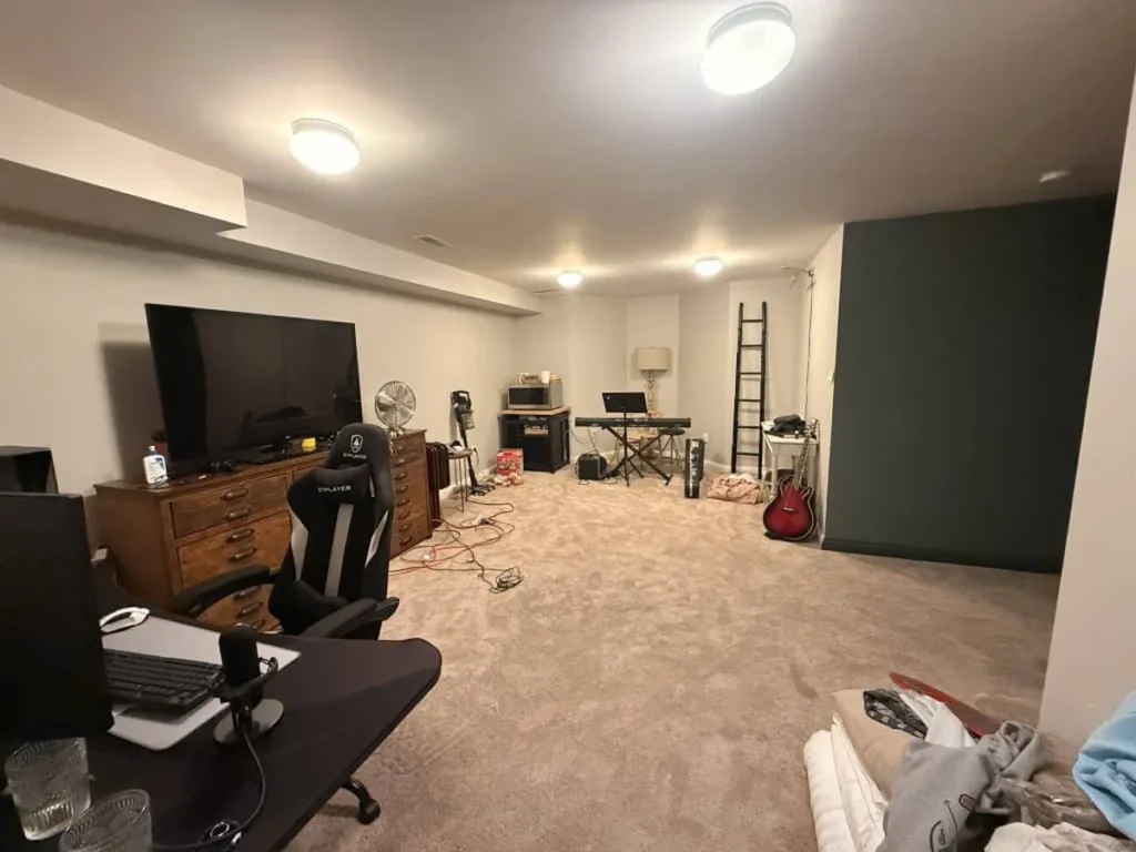 Unfinished basement corner with green accent wall before renovation