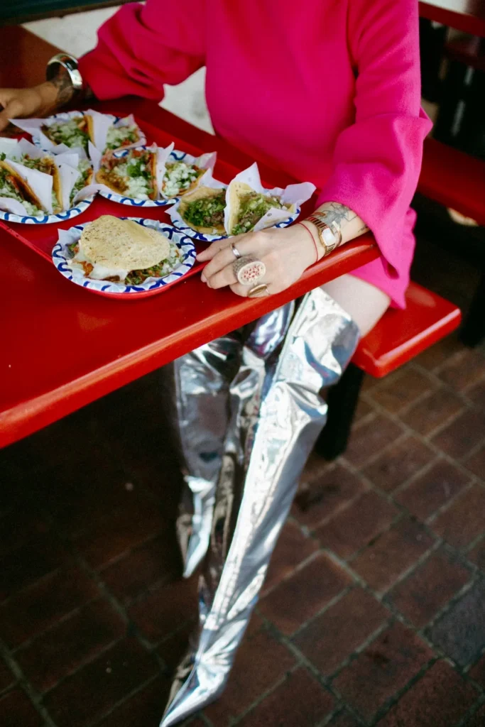 Chef Claudette Zepeda at a red table with tacos, styled look